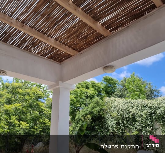 פרגולה מעץ בגינה עם כסאות ושמש
